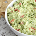 guacamole in a bowl next to toritilla chips