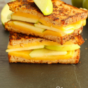 apple grilled cheese cut in half and stacked on black platter