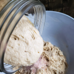 sourdough starter being poured into bowl on top of salt and flour